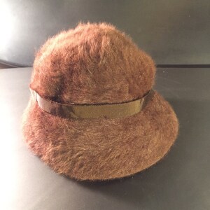 May include: A brown fuzzy bucket hat with a brown ribbon around the crown.