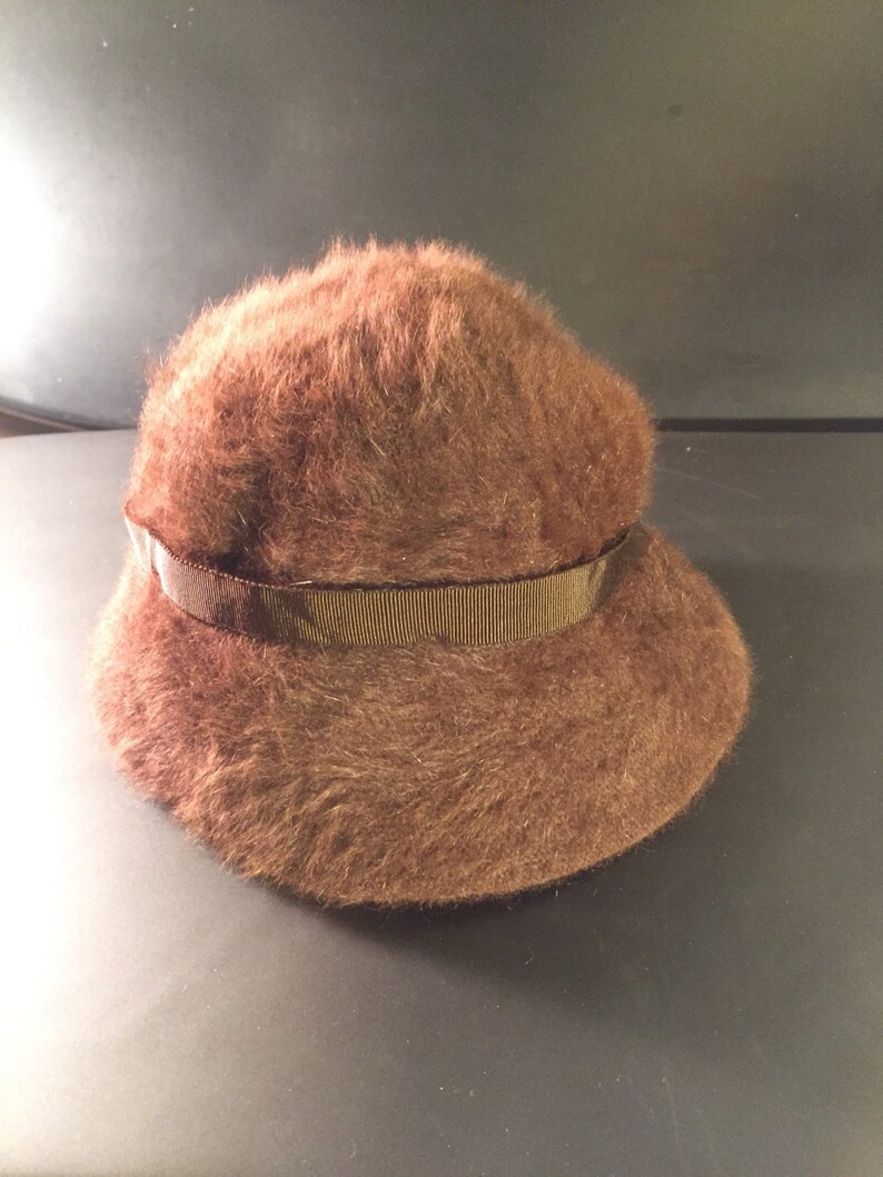 May include: A brown fuzzy bucket hat with a brown ribbon around the crown.