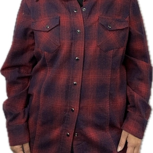 May include: A long-sleeved flannel shirt with a red and black plaid pattern. The shirt has a button-down front and two chest pockets.