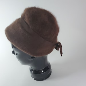 May include: A brown fuzzy bucket hat with a brown satin ribbon tied in a bow at the back.