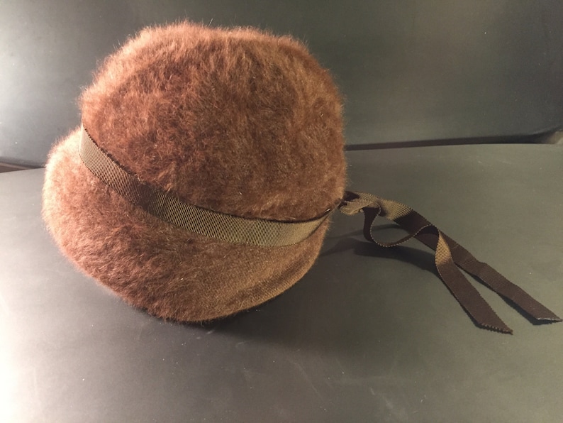 May include: A brown fuzzy hat with a brown ribbon tied around it.