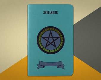 May include: A teal blue notebook with the word "SPELLBOOK" printed on the front cover. The cover features a black five-pointed star inside a circle of green and gold beads.
