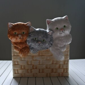 Peut inclure: Une figurine en céramique de trois chatons regardant par-dessus un mur de briques. Les chatons sont orange, gris et blanc.
