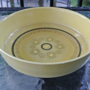 Puede incluir: Un taz&oacute;n grande de cer&aacute;mica amarilla con un dise&ntilde;o geom&eacute;trico marr&oacute;n y blanco. El taz&oacute;n est&aacute; vac&iacute;o y est&aacute; sobre una mesa de vidrio.