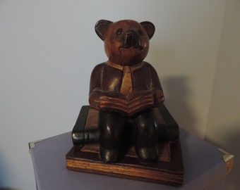 Wooden bear sculpture sitting on books