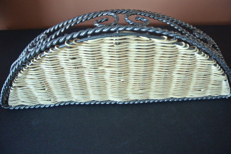 Pu&ograve; includere: Un porta tovaglioli in vimini semicircolare con una cornice in metallo nero. La cornice &egrave; decorata con un motivo a corda.