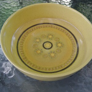 Puede incluir: Un taz&oacute;n de cer&aacute;mica amarillo con un borde marr&oacute;n y un patr&oacute;n decorativo de peque&ntilde;os c&iacute;rculos amarillos y l&iacute;neas marrones.