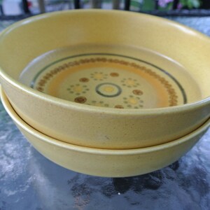 Puede incluir: Dos cuencos de cer&aacute;mica amarillos con un patr&oacute;n geom&eacute;trico marr&oacute;n y blanco. Los cuencos est&aacute;n apilados uno encima del otro.