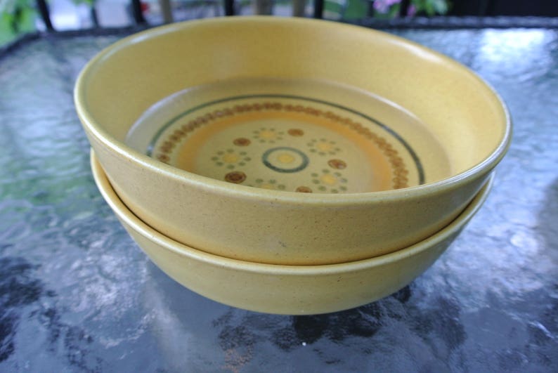 Puede incluir: Dos cuencos de cer&aacute;mica amarillos con un patr&oacute;n geom&eacute;trico marr&oacute;n y blanco. Los cuencos est&aacute;n apilados uno encima del otro.