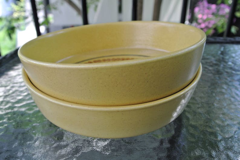 Puede incluir: Dos cuencos de cer&aacute;mica amarilla apilados uno encima del otro. Los cuencos tienen una textura moteada y una forma ligeramente redondeada.