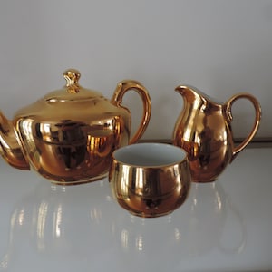 Puede incluir: Un juego de tetera, jarra de crema y azucarero chapado en oro. El juego está hecho de porcelana blanca con un acabado dorado brillante.