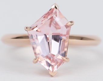 Puede incluir: Un anillo de oro rosa con una gran piedra preciosa rosa facetada engastada en una forma geométrica.
