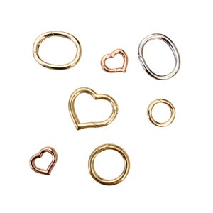 May include: Assortment of gold, silver, and rose gold metal rings and heart-shaped rings. The rings are all different sizes and styles.