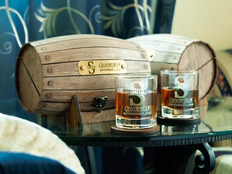 May include: Two personalised whiskey glasses with the text "Smith Groomman September 9, 2023" and a wooden barrel with a gold plaque that reads "Smith Groomman September 9, 2023".