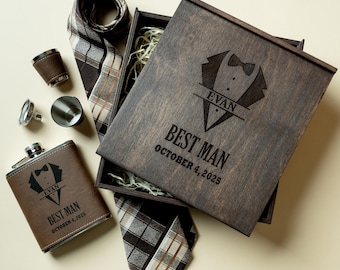 May include: A wooden box set containing a tie, flask, shot glasses, and cufflinks. The box and flask are engraved with a tuxedo design and the text "EVAN BEST MAN OCTOBER 4, 2025". The tie has a brown and tan plaid pattern. A gift set.