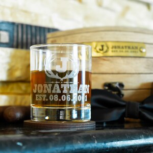 May include: A personalised whiskey glass with an etched design of antlers and the letter J. The glass also has the name Jonathan and the date 08.06.2001 etched on it.