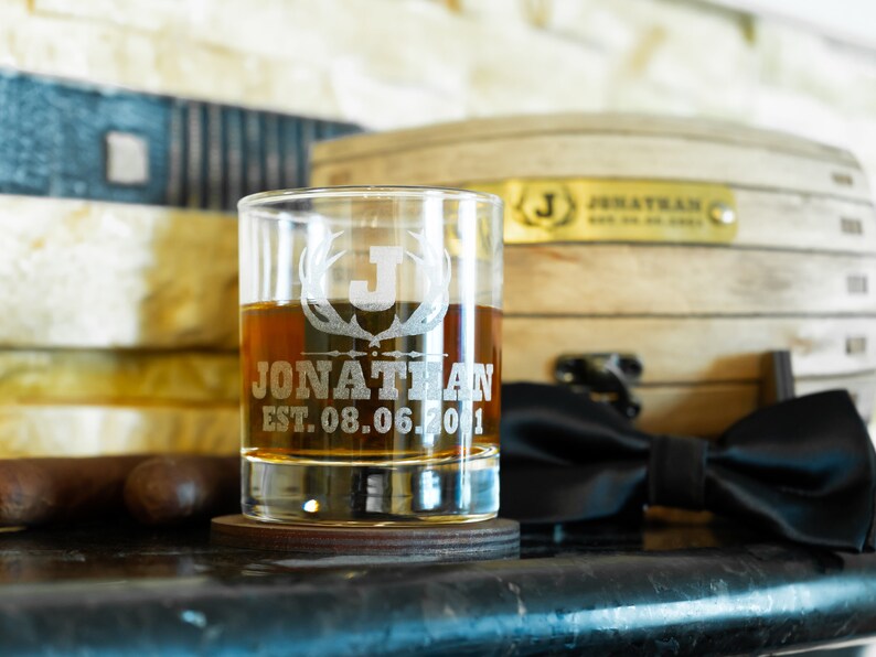 May include: A personalised whiskey glass with an etched design of antlers and the letter J. The glass also has the name Jonathan and the date 08.06.2001 etched on it.