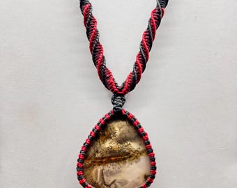 May include: A teardrop-shaped pendant necklace with a brown and white agate stone. The necklace is made with black and red cord.