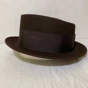 May include: A brown fedora hat with a wide brim and a black ribbon band.