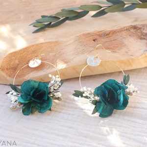 Op de afbeelding: Een paar gouden creolen met een teal velvet bloem en witte gedroogde bloemen bevestigd aan elke creool.