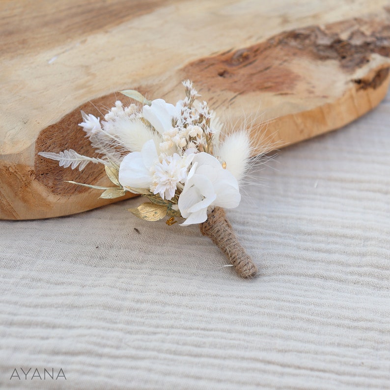 May include: A small bouquet of dried flowers in shades of white and gold, tied with twine. The bouquet includes white flowers, dried grasses, and gold accents.