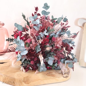 May include: A dried flower bouquet with pink, burgundy, and white flowers, and blue-green eucalyptus leaves.