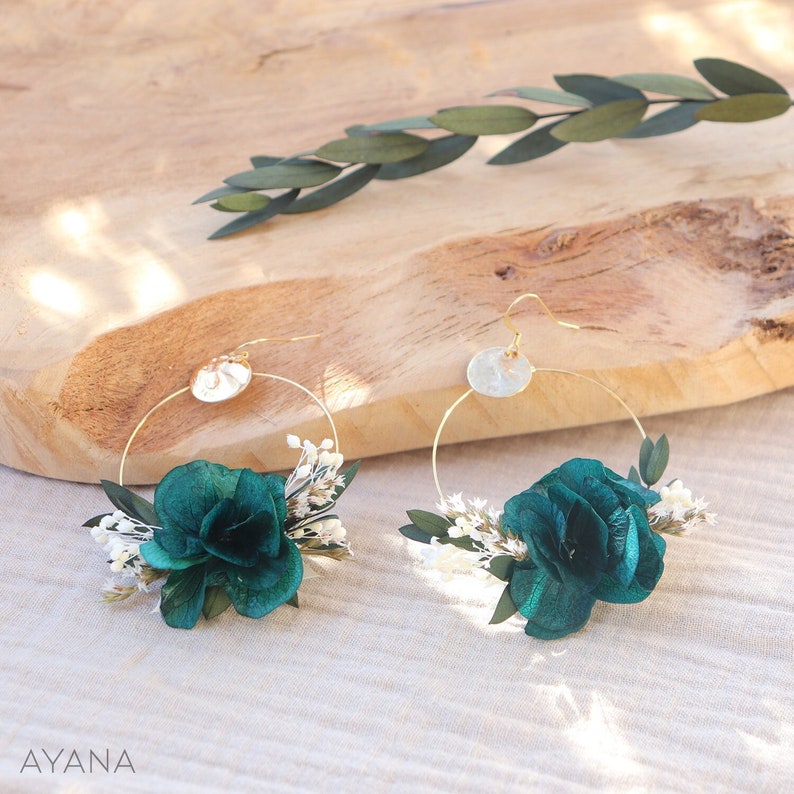 Op de afbeelding: Een paar gouden creolen met een teal velvet bloem en witte gedroogde bloemen bevestigd aan elke creool.