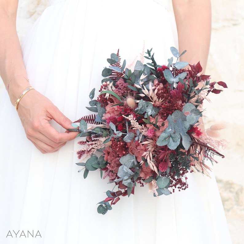 May include: A bouquet of dried flowers in shades of burgundy, pink, and green. The bouquet includes eucalyptus, ferns, and other dried flowers.