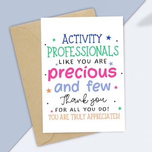 May include: A white greeting card with colorful text, including "ACTIVITY PROFESSIONALS" and "precious and few." The card is inside a brown envelope, set against a light blue background. The message is a thank you note.