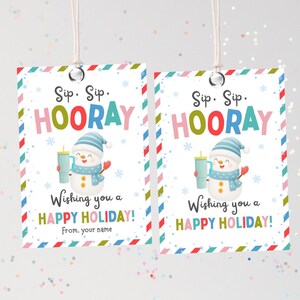 Puede incluir: Dos etiquetas de regalo navideñas con un diseño de muñeco de nieve. Las etiquetas tienen un borde colorido y dicen "Sip Sip Hooray" y "Wishing you a Happy Holiday!". El muñeco de nieve lleva un gorro y bufanda azules y sostiene una bebida.