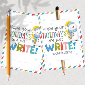 May include: Two holiday-themed cards with pencils. The cards feature a snowman illustration and the text "Hope your HOLIDAYS are just WRITE!" in colorful letters. One card has a pencil on the left, the other on the right.
