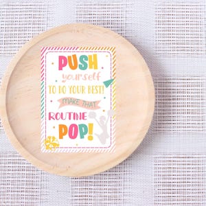 May include: A pink, yellow, and green motivational poster with the text "PUSH yourself to do your best! Make that ROUTINE POP!" and a silhouette of a cheerleader holding pom-poms.