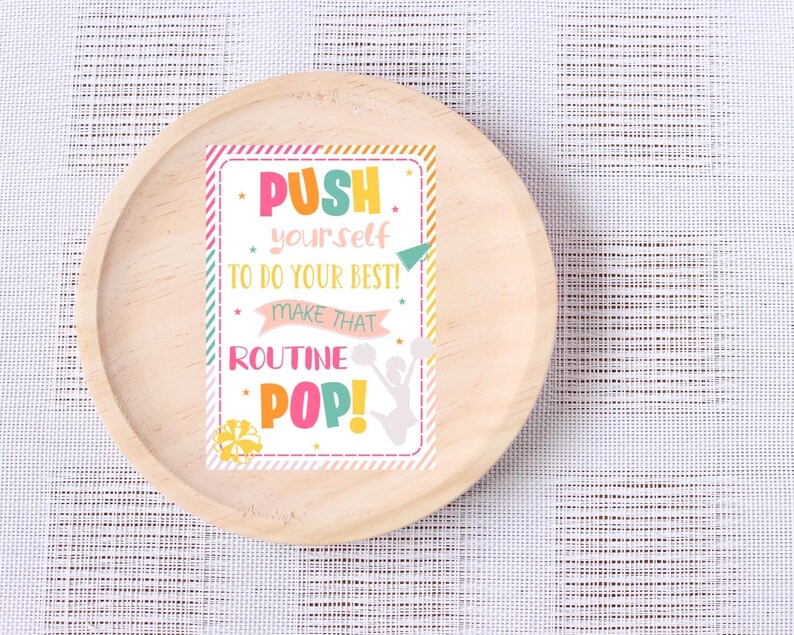 May include: A pink, yellow, and green motivational poster with the text "PUSH yourself to do your best! Make that ROUTINE POP!" and a silhouette of a cheerleader holding pom-poms.