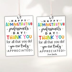 Könnte beinhalten: Zwei weiße Geschenkanhänger mit dem Text "HAPPY ADMINISTRATIVE PROFESSIONALS DAY! THANK YOU for all that you do! You are truly APPRECIATED!" in bunten Buchstaben. Die Anhänger hängen an einer weißen Schnur.