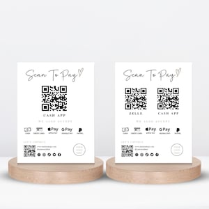 Op de afbeelding: Twee witte borden met zwarte tekst en QR-codes. De borden zeggen "Scan To Pay" en sommen verschillende betaalmethoden op, waaronder Cash App, Zelle, Apple Pay, Google Pay en PayPal.