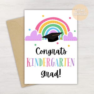 May include: A white graduation card with a rainbow, mortarboard, and the words "Congrats Kindergarten grad!" in colorful text. The card is paired with a brown envelope, perfect for celebrating a kindergarten graduation.