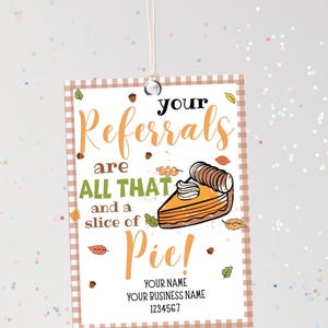 May include: A gift tag with a tan and white checkered border. The tag features the words "your Referrals are ALL THAT and a slice of Pie!" in orange and black text. A slice of pie with whipped cream is illustrated on the tag. Acorns and leaves are scattered around the text.