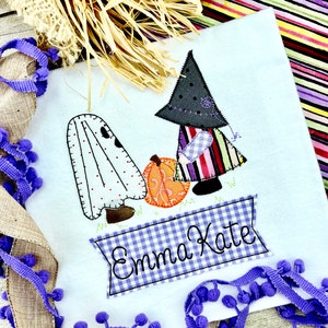 May include: A white onesie with a ghost and witch applique. The witch is holding a pumpkin and the onesie is personalized with the name "Emma Kate".