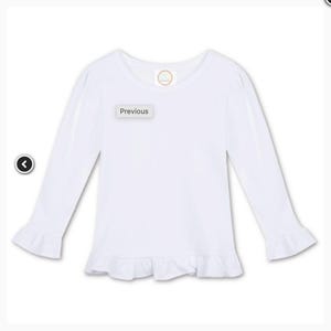 May include: A white long-sleeved shirt with ruffle detailing at the cuffs and hem. The shirt has a round neckline and a small circular logo near the neckline. The word "Previous" is displayed on a small rectangular label.