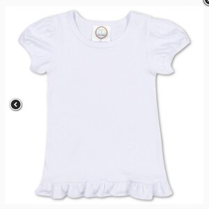 May include: A white short-sleeve shirt with a round neckline and ruffled hem. The sleeves have a puffed design. A small, circular tag is sewn on the neckline.