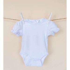 May include: White baby onesie with short sleeves and a ruffled trim. The onesie has a round neckline and a snap closure at the bottom.