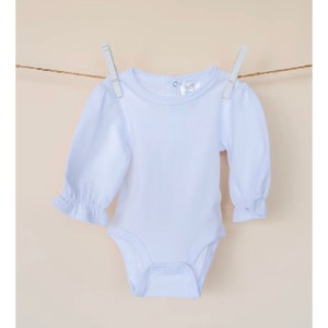 May include: A white long-sleeved baby bodysuit with a ruffled sleeve detail. The bodysuit has a round neckline and a snap closure at the crotch.