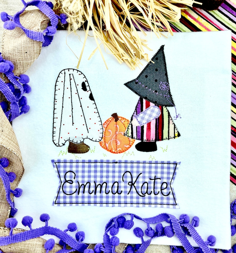 May include: A white fabric ghost and a witch with a black hat and striped dress stand next to a pumpkin. A blue and white gingham banner reads "Emma Kate".