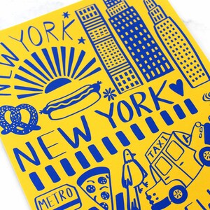 May include: A yellow background with blue illustrations of New York City landmarks, including the Empire State Building, a hot dog, a pretzel, a slice of pizza, a taxi cab, and the words "New York" and "Metro".