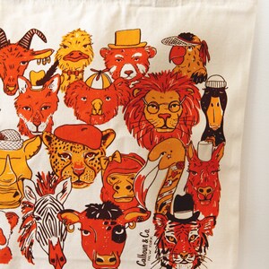 May include: A white canvas tote bag with a colorful illustration of various animals wearing hats. The animals include a lion, a tiger, a zebra, a cow, a monkey, a duck, a koala, a goat, a fox, a llama, a cheetah, a rhinoceros, and a parrot. The text "Calhoun & Co. NEW YORK" is printed on the bag.