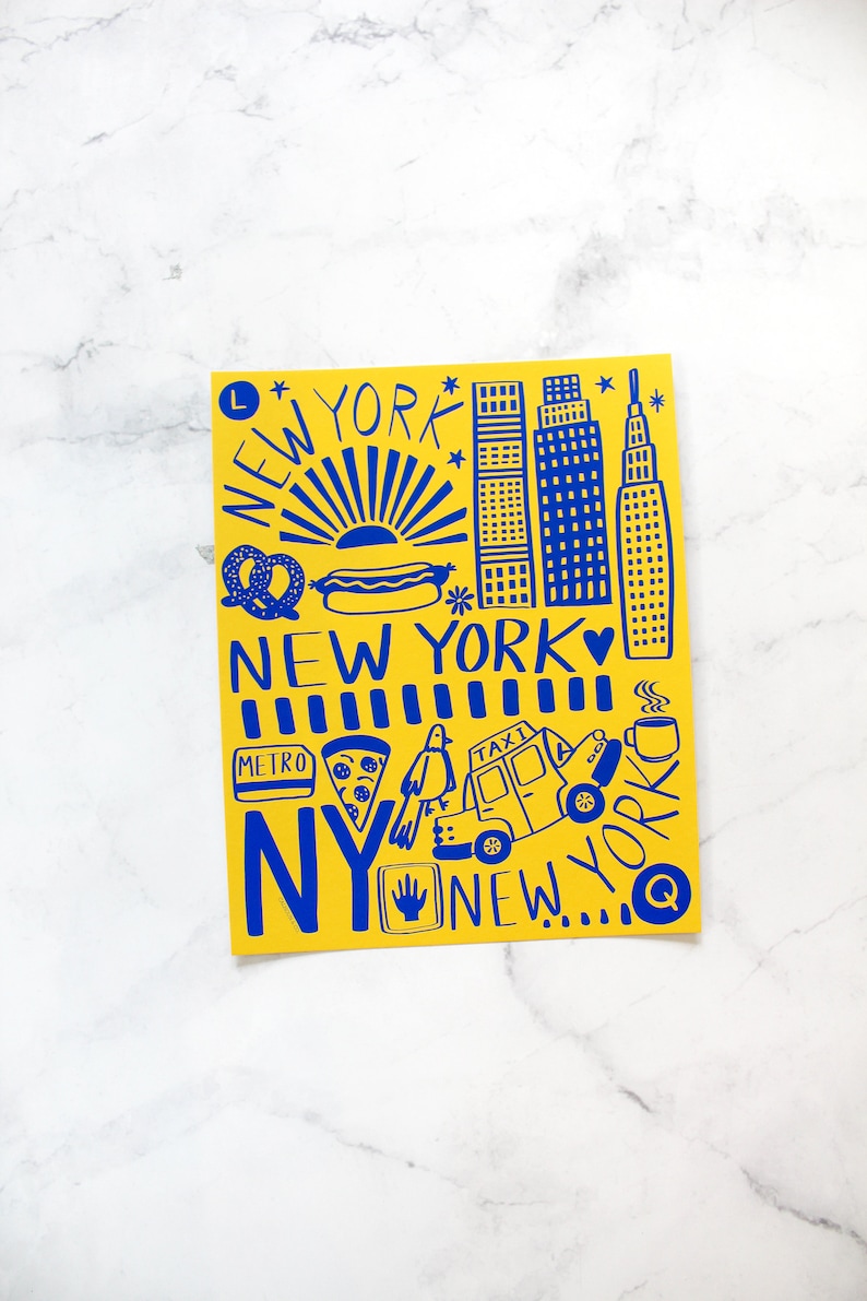 May include: A yellow card with blue illustrations of New York City landmarks, food, and transportation. The text "NEW YORK" appears multiple times on the card.
