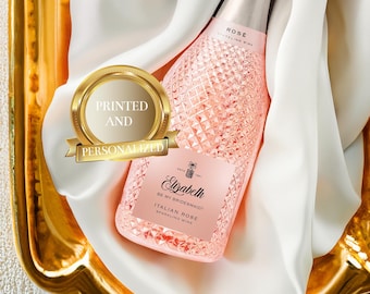 Può includere: Una bottiglia di vino spumante rosa con un'etichetta che dice "Elizabeth Be My Bridesmaid! Italian Rose Sparkling Wine". La bottiglia è su un vassoio dorato con un panno bianco.