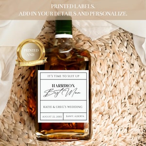 May include: A white label with black text on a brown glass bottle. The label reads "It's time to suit up. Harrison Best Man. Katie & Greg's Wedding. August 22, 20XX Banff, Alberta."