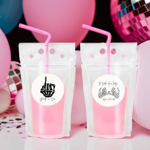May include: Two clear plastic pouches with pink liquid and pink straws. Each pouch has a round sticker with a black skeleton hand design. One sticker says "Boop - Do" and the other says "The Death of a Party! Megan & Bachelor".