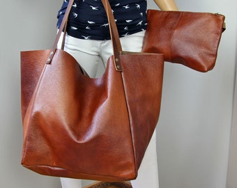 Könnte beinhalten: Eine große braune Ledertasche mit einer kleineren passenden Ledertasche. Die Tote Bag hat zwei lange Trageriemen und eine breite Öffnung.